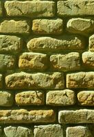 Vertical wall texture of several rows of very old brickwork made of red brick. Shattered and damaged brick wall with pinched corners photo