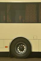 Photo of the hull of a large and long yellow bus with free space for advertising. Close-up side view of a passenger vehicle for transportation and tourism