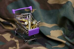 Rifle cartridges in small shopping cart. Big caliber ammo cartridges with a small shopping basket photo