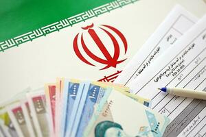 Iranian annual income tax return form F20-25-006 ready to fill on table with pen and iranian money on flag photo