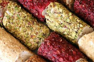 Rolls of turkish delight with many different flavors and fillings close up on table of vendors market photo