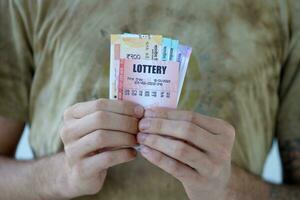 Man hands with indian rupees bills and lottery ticket. Concept of gambling and winning money in indian lottery photo