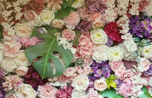 Floral background. Lot of artificial flowers in colorful composition on handmade wooden pink background photo