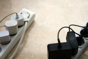 Overloaded power boards. Power strips with different electrical plugs on white floor photo