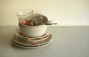 Stack of dirty dishes with food leftovers on the table after meal. Banquet ending concept. Unwashed dishes photo