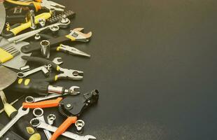 Handyman tool kit on black wooden table. Many wrenches and screwdrivers, pilers and other tools for any types of repair or construction works. Repairman tools photo