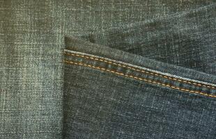 Detailed abstract texture of dark blue denim cloth. Background image of old used denim trousers fabric photo