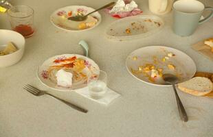 Empty dirty plates with spoons and forks on the table after meal. Banquet ending concept. Unwashed dishes photo