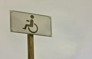 A road sign indicating the crossing of a road for disabled people. White road sign with a picture of a man sitting in a wheelchair photo