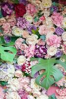 Floral background. Lot of artificial flowers in colorful composition on handmade wooden pink background photo