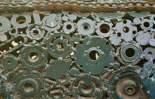 A composition of a set of gears and car parts that are welded to each other and painted green. Grunge steampunk texture photo