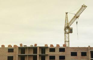 View of a large construction site with buildings under construction and multi-storey residential homes. Tower cranes in action on blue sky background. Housing renovation concept photo