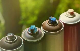 A few used aerosol paint sprayers lie on the windowsill in the workshop of a graffiti artist. The concept of street art and illegal drawing on the walls. Youth hobby photo