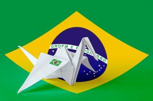 Brazil flag depicted on paper origami crane wing. Handmade arts concept photo
