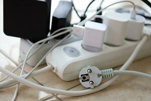 Overloaded power boards. Power strips with different electrical plugs on white floor photo