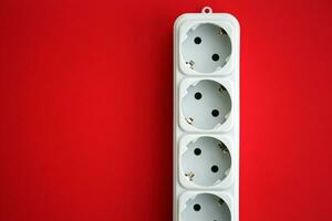 White electrical multi plug extender with european socket on bright red background photo