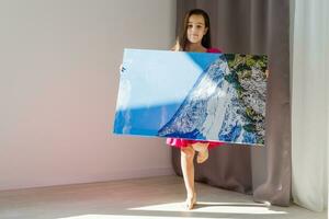 A happy little girl holds canvas at home photo