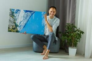 man holds photo canvas at home