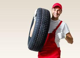 working man in full growth holds a tire on a white background photo