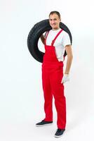 Mechanic carrying a tyre on a white background photo