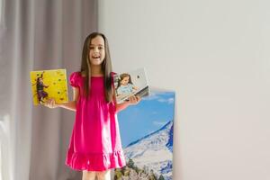 A happy little girl holds canvas at home photo