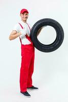trabajando hombre en lleno crecimiento sostiene un neumático en un blanco antecedentes foto