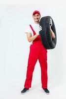 Portrait of smiling male mechanic holding tire on white background photo