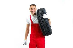 Portrait of smiling male mechanic holding tire on white background photo