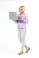 Smiling lovely stylish woman holding laptop computer while standing over white background photo