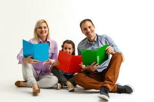 Family reading a book together lying on the floor at home photo