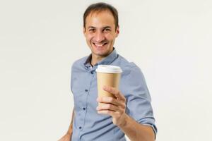Happy young man in a shirt holds a cup of coffee in his hands, looks into the camera and smiles, isolated on a white background. photo