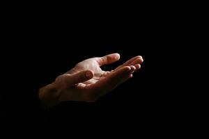 Handsome man sit prayer on black background. His hands are praying for God's blessings. photo