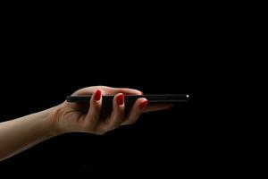 mujer manos utilizando moderno móvil teléfono en negro antecedentes foto