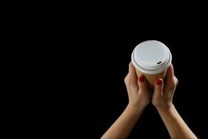 Female hand with paper cup isolated on black photo