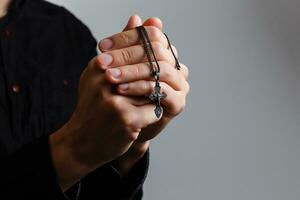 man prays with a cross on a black background photo