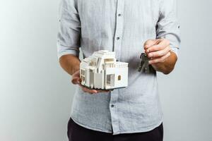 man in casual clothes posing isolated on white wall background. Holding in hands house and bunch of keys photo