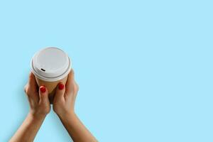 Female hand with paper cup isolated on blue photo