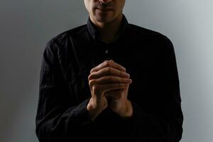 Portrait of a handsome man praying over gray background photo