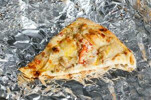 Last food piece of popular pizza on foil photo