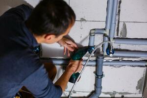 plumber makes wiring of sewer pipes photo