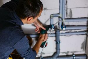 Close-up Of A Male Plumber repairs pipes in the toilet photo