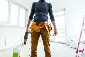 The builder in a protective helmet holds the professional puncher-hammer with a drill of the big diameter photo