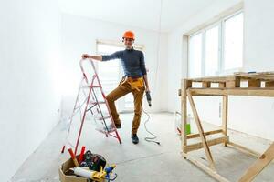 The builder in a protective helmet holds the professional puncher-hammer with a drill of the big diameter photo