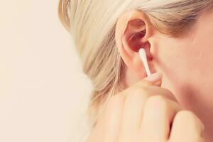 A young, beautiful, happy woman cleans her ear photo