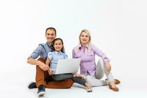 Happy family lying down on the floor while surfing on internet online with laptop, isolated over white photo
