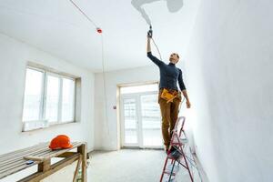 Builder worker with pneumatic hammer drill perforator equipment making hole in wall at construction site photo