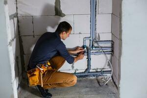 plumber makes wiring of sewer pipes photo