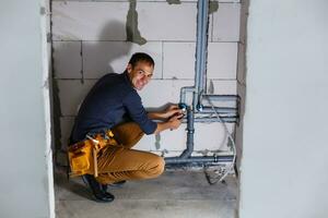 plumber makes wiring of sewer pipes photo