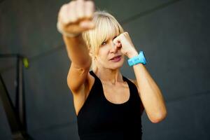 Strong female fighter performing martial art punch in fitness club photo