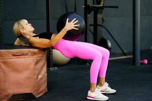 Determined female exercising with ball in fitness gym photo